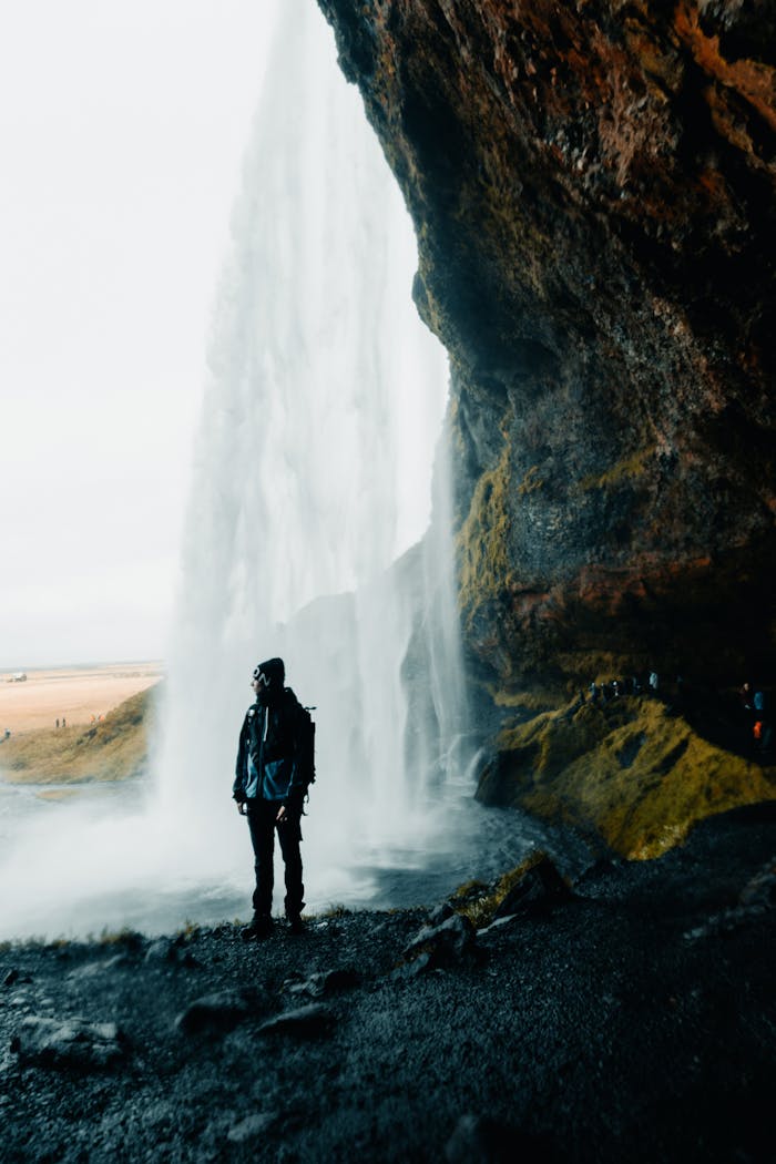Silhouette of a person standing by a powerful waterfall, capturing nature's beauty and adventure.
